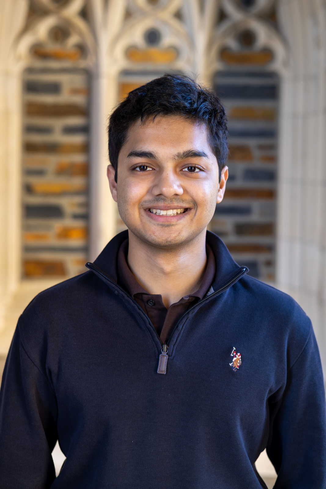 Avihan smiling in front of Duke's stone arches